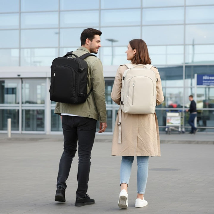 Couple home et femme portant des Sacs à Dos Cabine 40x20x25 noir et beige devant un aéroport, format cabine.