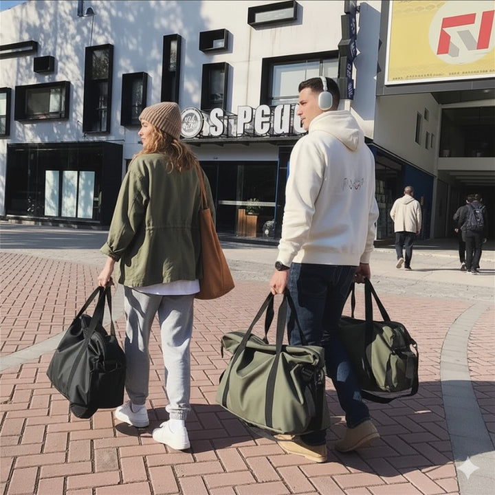 Couple en déplacement portant deux sacs fourre tout de voyage kaki et noir, usage mixte homme et femme.
