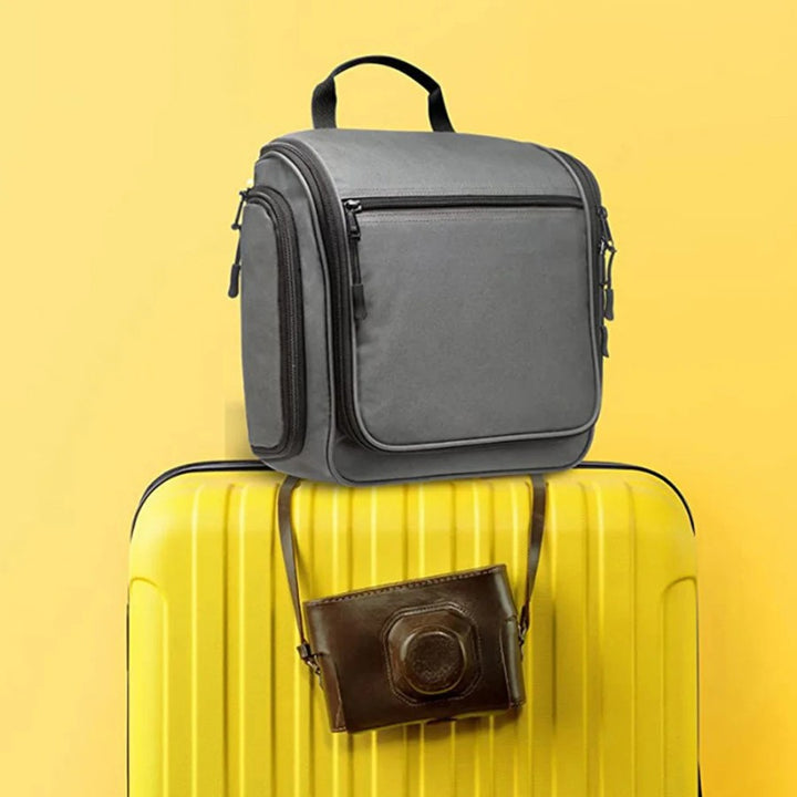 Trousse de toilette de voyage posée sur une valise cabine, format compact idéal pour déplacements.