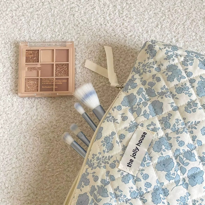 Trousse de toilette fleurie matelassée bleue ouverte avec pinceaux de maquillage