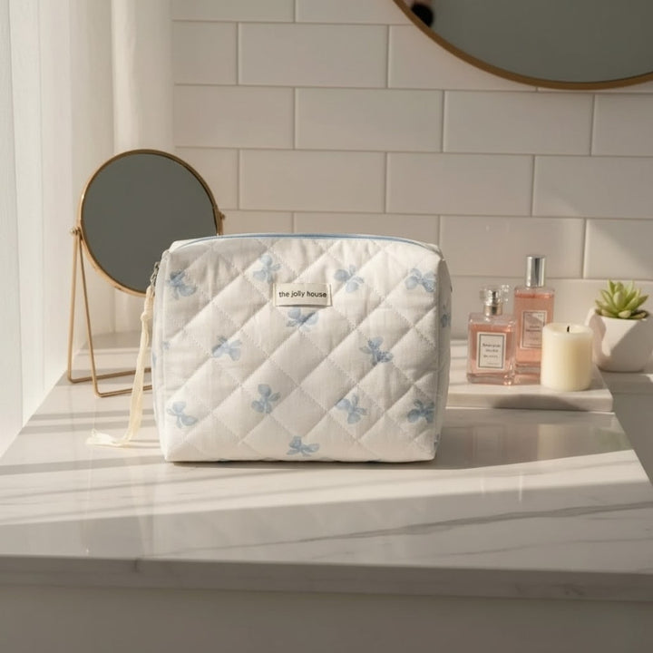 Grande trousse de toilette tissu matelassé nœuds bleus sur plan de toilette en marbre