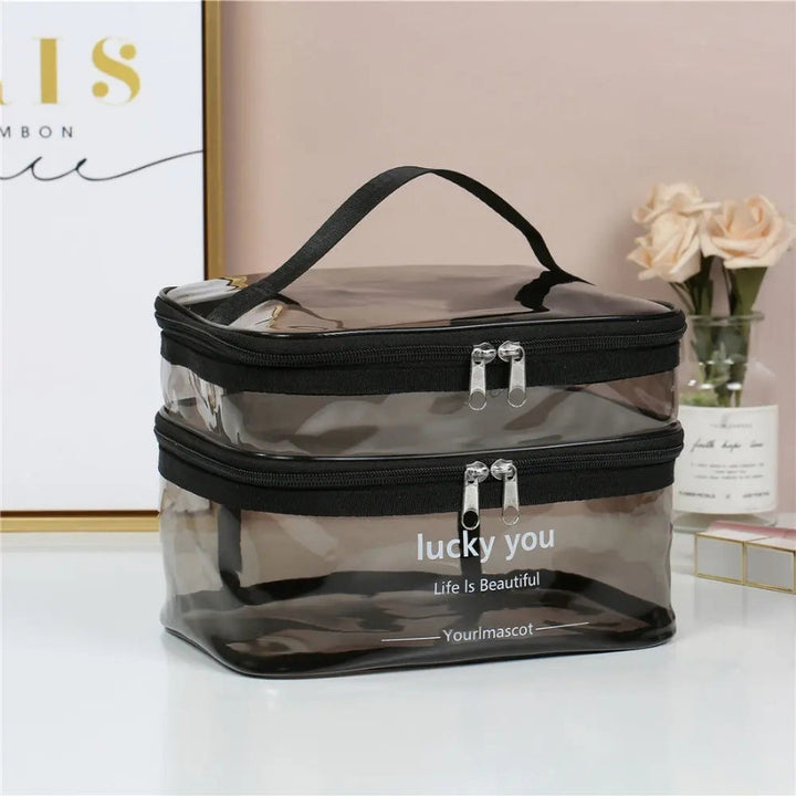 vanity case transparent noir double compartiment posé sur une coiffeuse